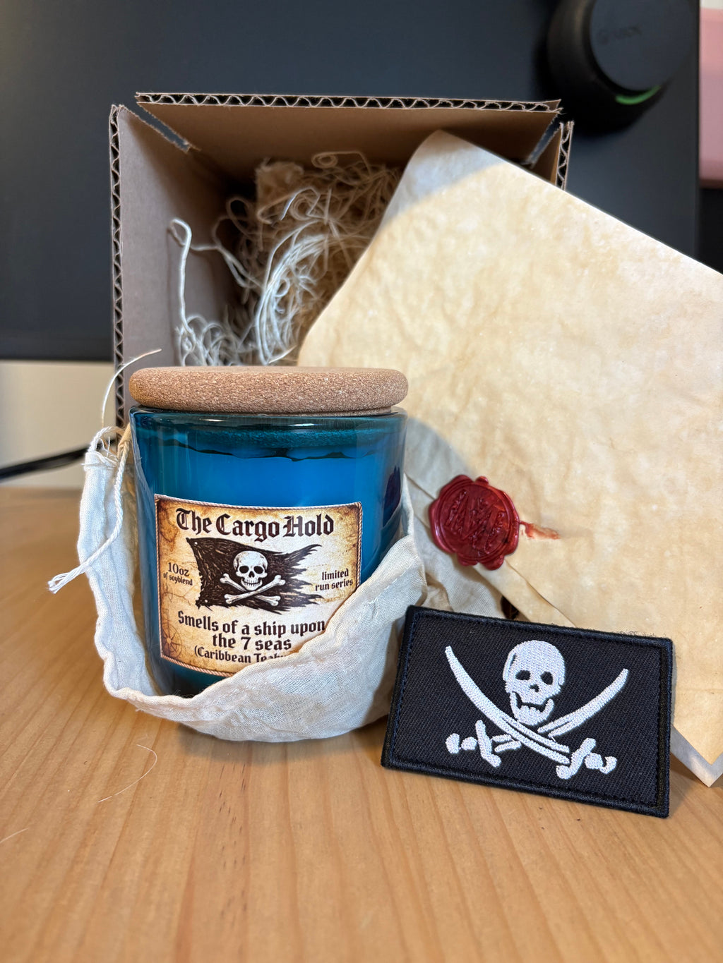 The Cargo Hold - Caribbean Teakwood Candle with packaging and pirate patch